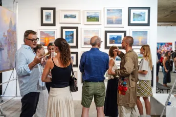 Visitors browsing a wall of framed paintings at the Urban Echoes exhibition