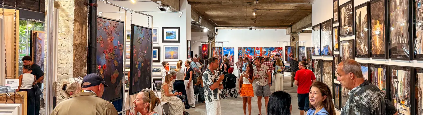 Paul Kenton's framed cityscape paintings lining the walls of the industrial gallery at the Urban Echoes exhibition