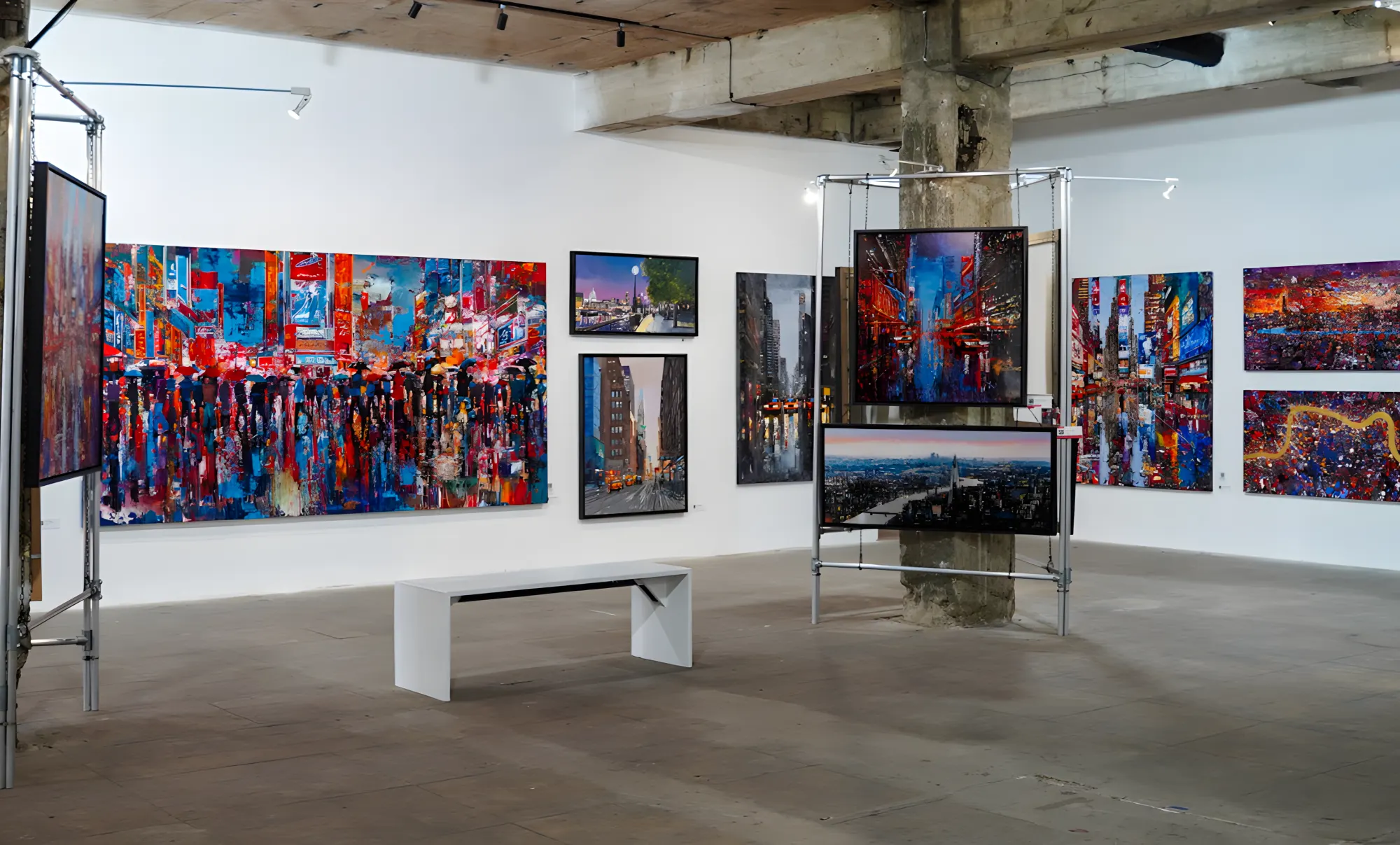 A wide view of the Urban Echoes exhibition at The Bomb Factory, with Paul Kenton's colourful cityscape paintings filling the industrial gallery walls